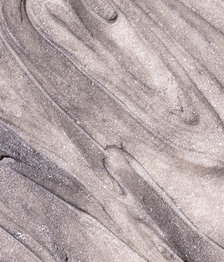 Close-up of edible glitter dust in Chrome showcasing a silver shimmer with a swirled texture on a neutral background