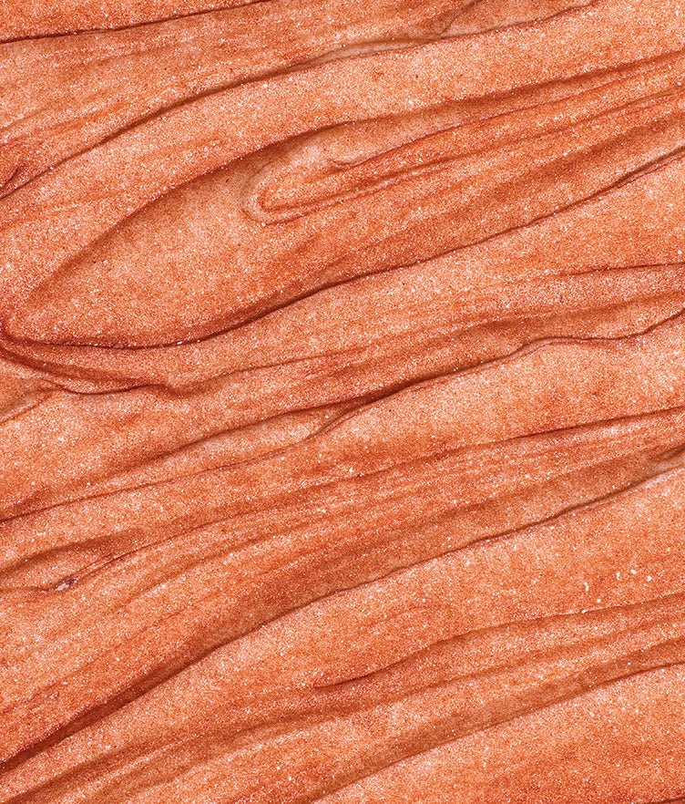 Close up of Edible Glitter Dust in Rosé Gold showing its fine shimmering texture on a peach toned surface