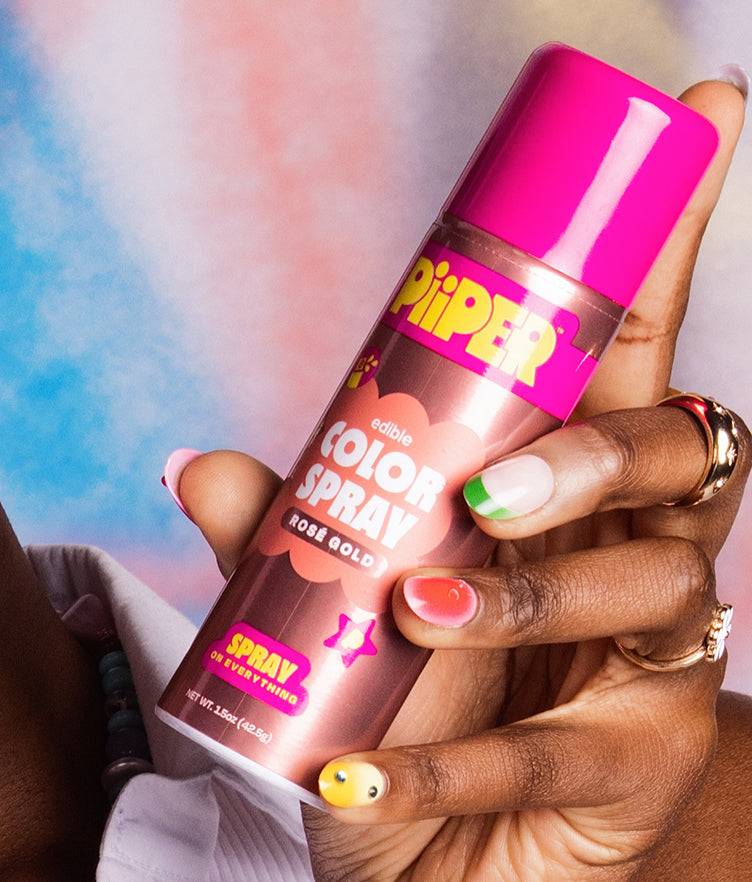 Close-up of PiiPER edible Color Spray in Rosé Gold showcasing the labeled can against a colorful background
