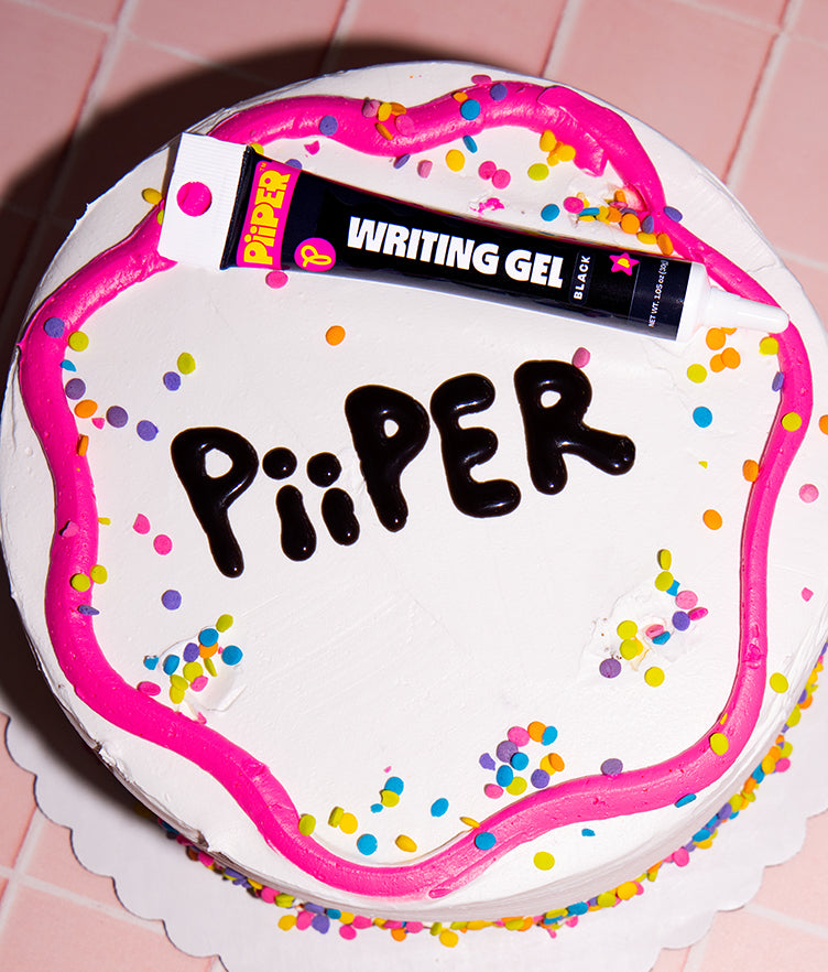Top view of PiiPER Writing Gel Black 30g tube with pointed tip on a decorated cake