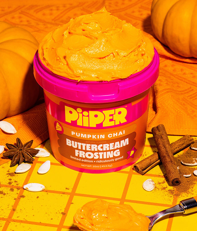 Front view of PiiPER Pumpkin Chai Buttercream Frosting showcasing open orange frosting with pumpkins, spices, and spoon