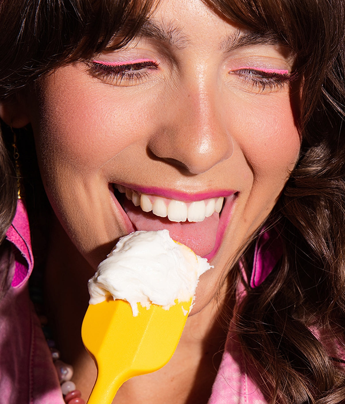 Woman eating Vanilla Vibes buttercream frosting from a yellow spatula